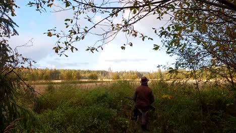 hunter man with shotgun waits patiently while enjoying beautiful rainbow and scenery