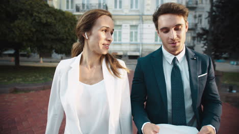 friendly business man and lady talking about documents on street walk.