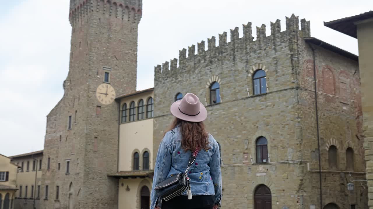 mujer paseando fuera del palacio dei priori de arezzo en la toscana, italia