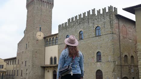 woman strolling outside the palazzo dei priori of arezzo in tuscany, italy