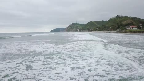 Aerial-drone-view-of-waves-splashing-at-the-shore-of-Olon-beach-in-Ecuador