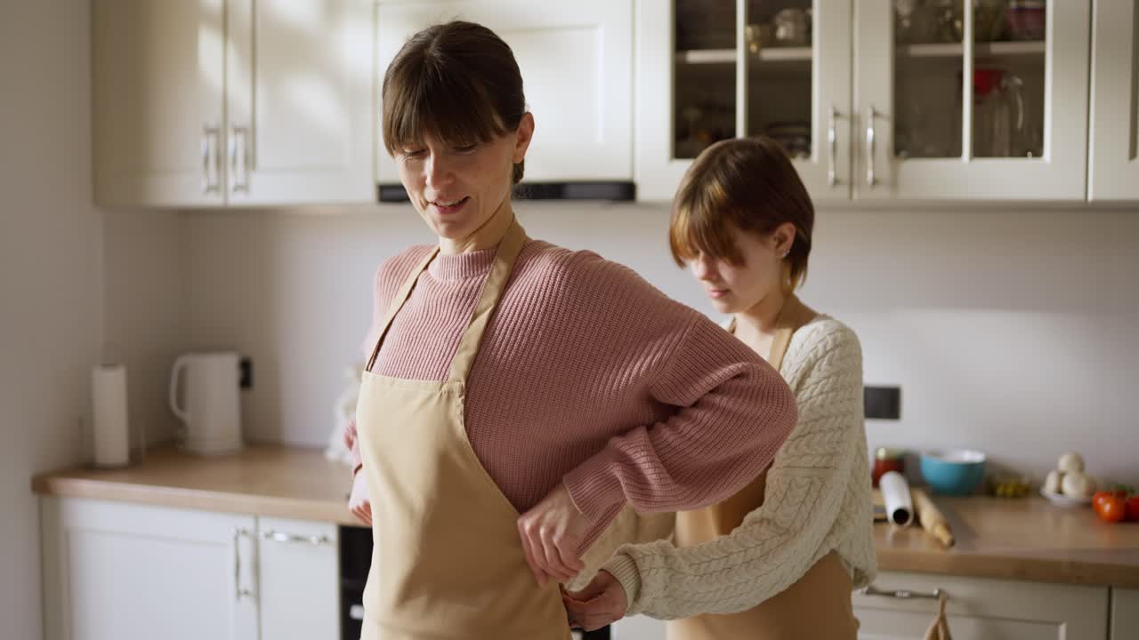 Mother and daughter wearing aprons in the kitchen