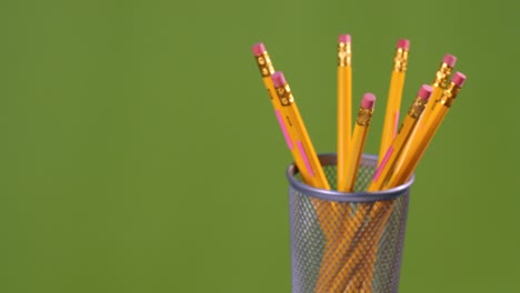 yellow eraser pencils turning on a green background