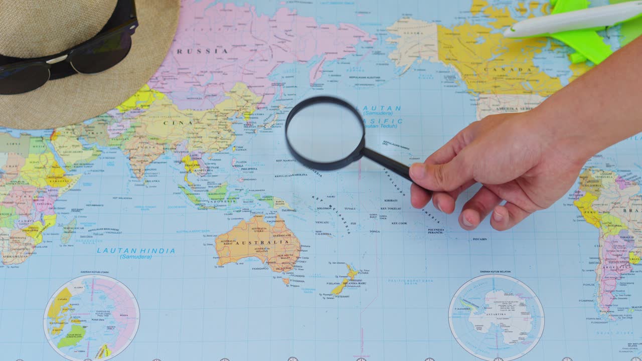 Close-up of traveler searching for destinations on world map with magnifying glass