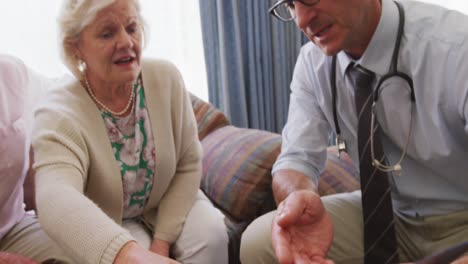 senior couple talking with a doctor in retirement house