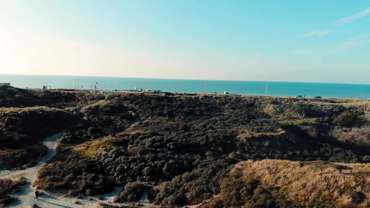 vista aérea de la carretera costera de la playa alejarse sobre el paisaje de dunas y el cielo azul