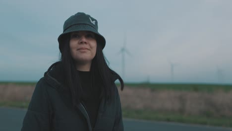 young caucasian woman with black hair, bucket hat, turn around outdoors