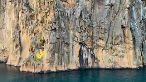 Rock-formations-and-calm-water-at-Vestmannaeyjar-in-Iceland,-close-POV