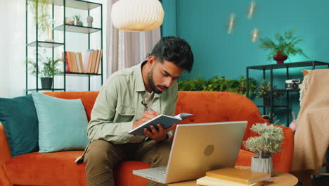 Indian-man-student-study-at-home-on-laptop-computer-making-conference-video-call-talking-to-webcam