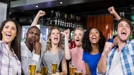 happy diverse female and male sport fans watching game at bar, cheering and drinking