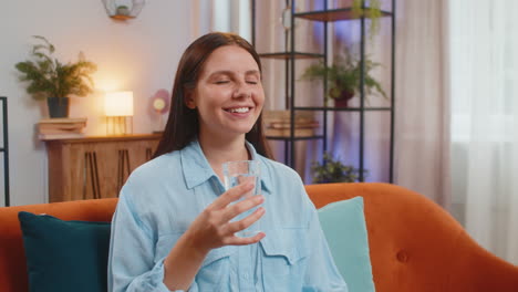 mujer joven sedienta en casa sosteniendo un vaso de agua natural hacer sorbos bebiendo agua filtrada