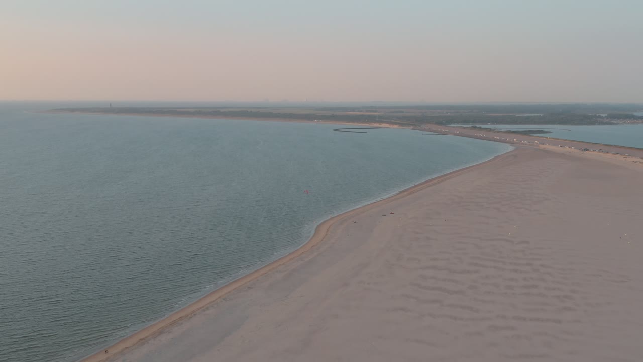 drone cinemático - toma panorámica aérea de la playa de arena natural al atardecer con turistas y personas con buggykiting en zelanda en el mar del norte, países bajos, 25p