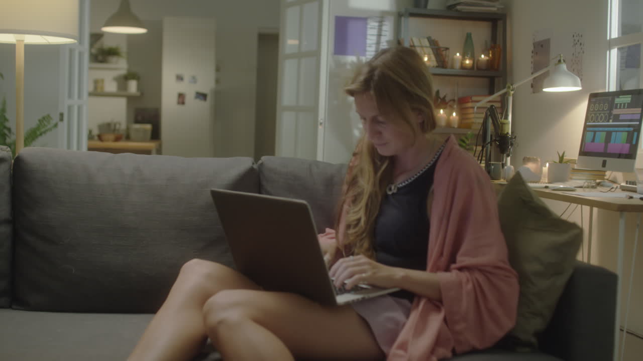 Woman Using Laptop of Sofa at Home