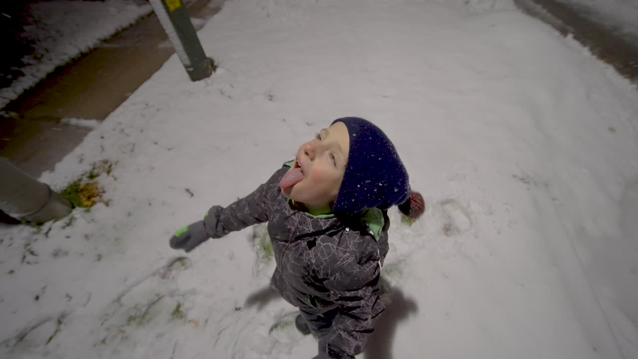 lindo niño atrapando copos de nieve en su boca