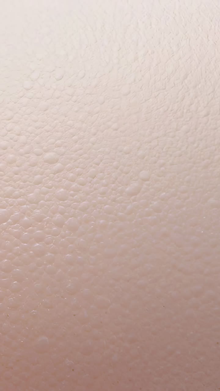 Vídeo vertical: La cámara de grabación se mantiene estable en primer plano en la pared interior, mostrando una textura punteada
