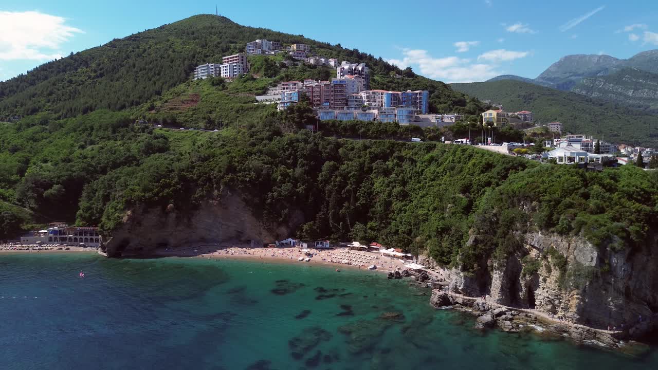 Mogren beach by cliff in Budva on Adriatic coast, Drone shot