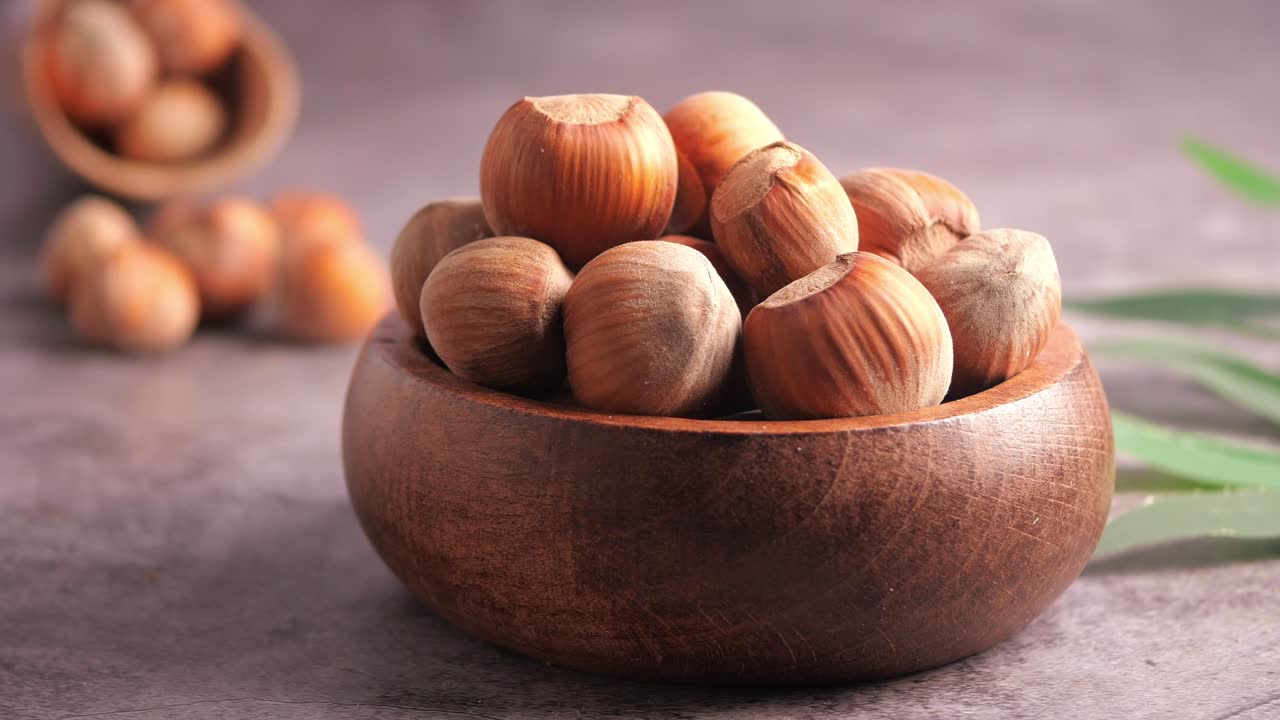 Primo piano di una mano che prende una nocciola da una ciotola di legno