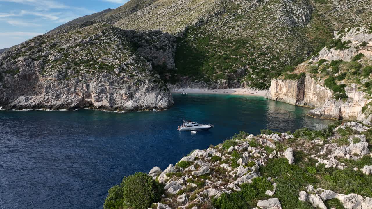 Yacht Anchored in Beautiful Cove - Aerial Orbit with Cliffs Foreground