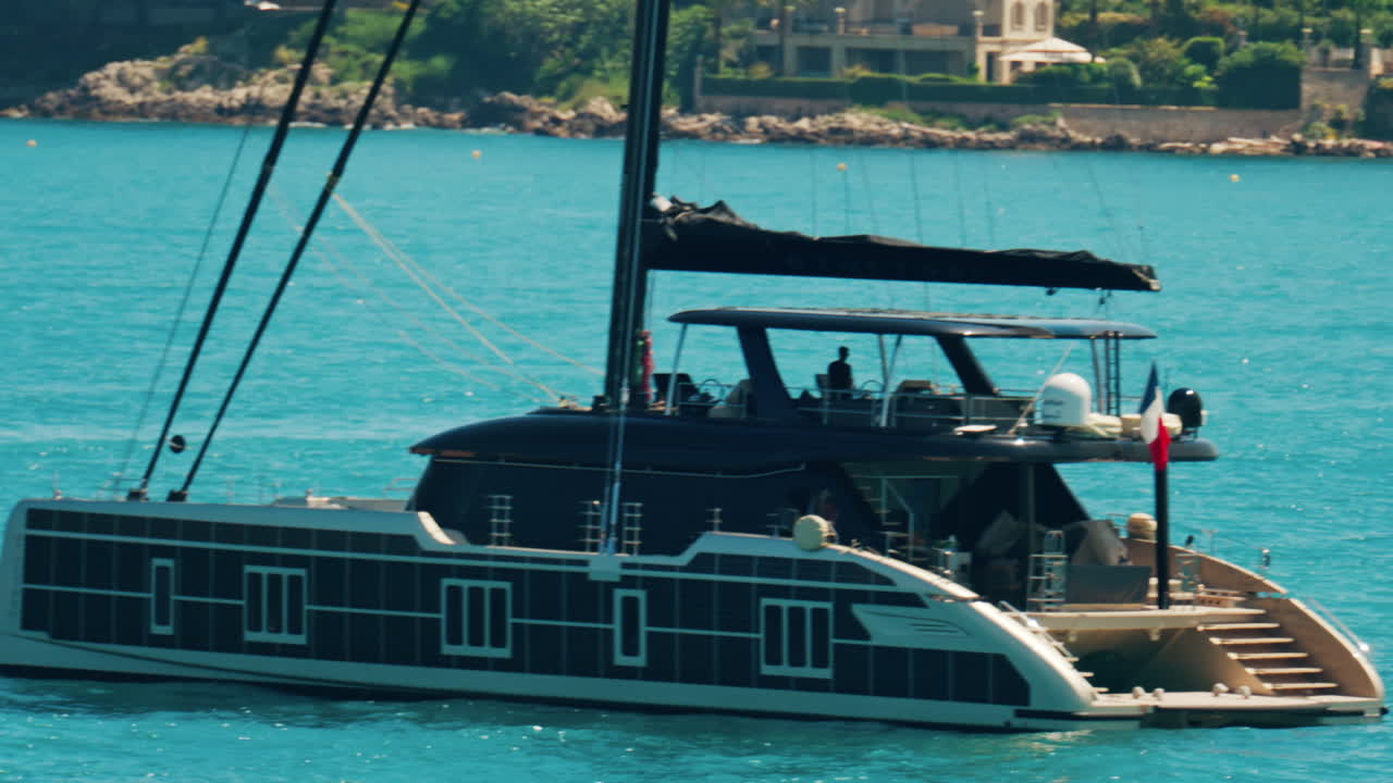 Antibes, France - May 24, 2025: Boat floating on the Mediterranean sea with villas surrounded by greenery in the background