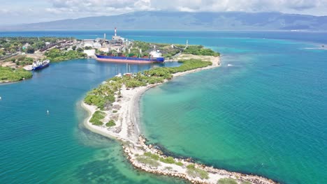 aerial shot showing port of barahona with industrial ship docking surrounded by caribbean sea in summer