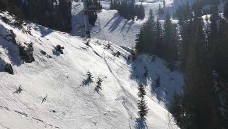 Aerial-view-from-ski-chairlift-on-skiers-below-with-scenic-pine-trees-on-the-slopes