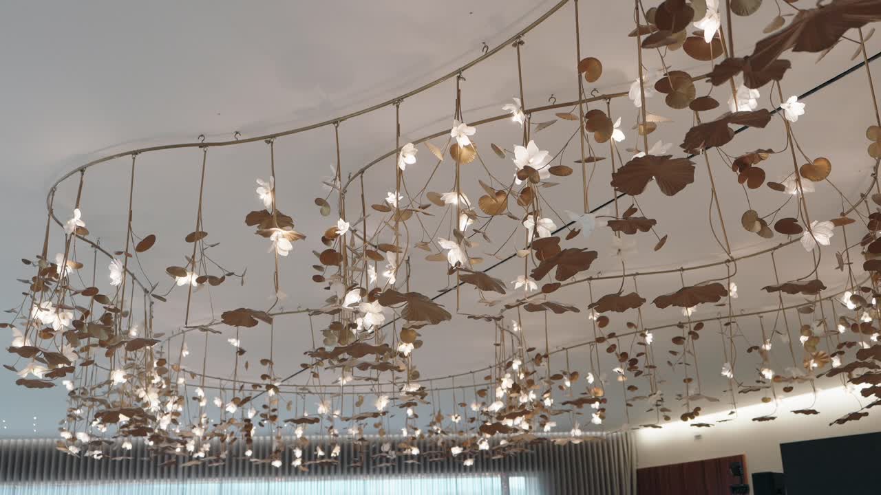 illuminated ceiling art with white flowers and golden hanging leaf elements