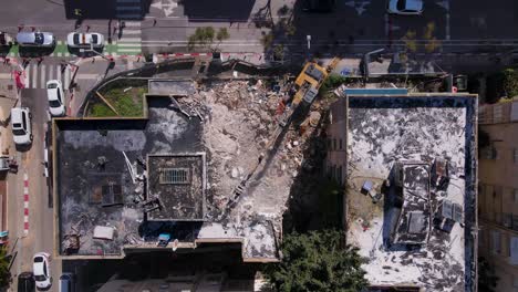 aerial view of a demolished building with urban surroundings and excavator working on site