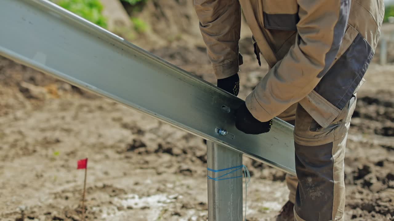 Solar panels installation. Worker in orange hard hat is installing metal frame. Metal basis for photovoltaic panel outdoors. Close-up.