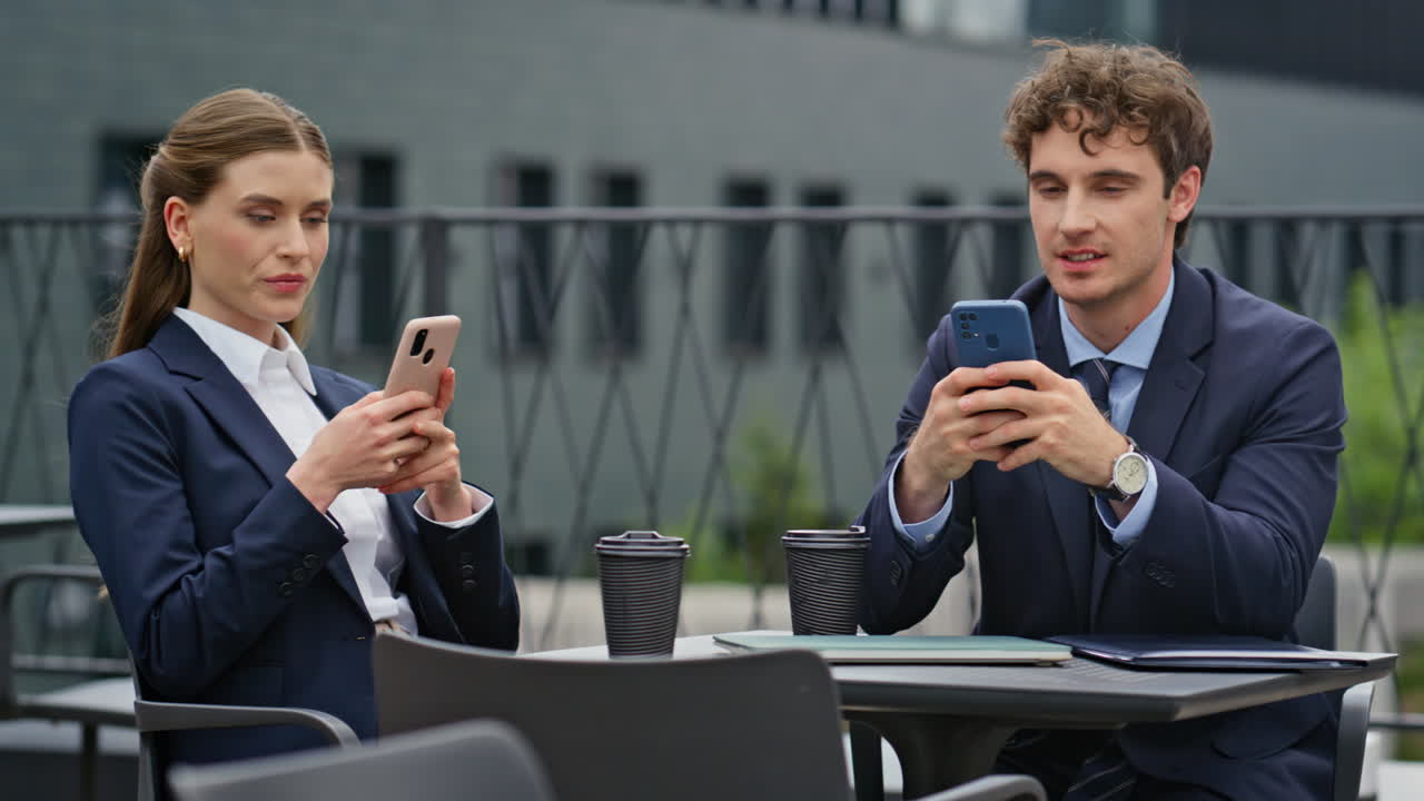 Business people focused smartphones at work break in outdoors cafeteria closeup