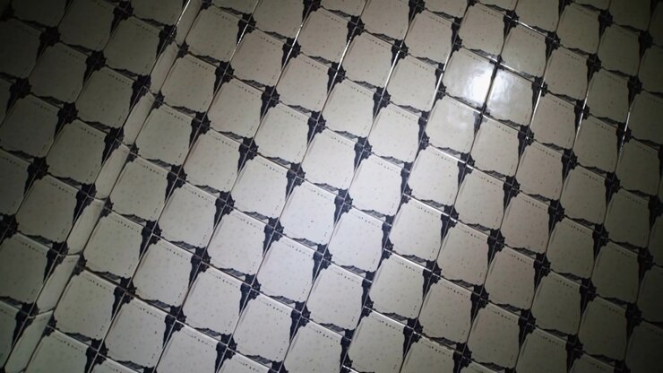 Tilting handheld camera recording glossy ceramic tile grid at room wall, capturing close-up shine