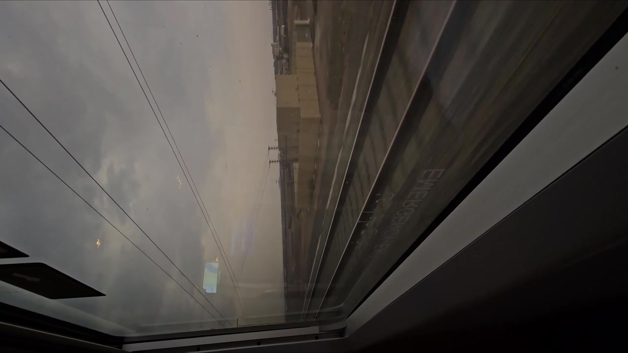 Vídeo vertical da vista da janela de um trem, tarde no deserto, movimento rápido, terra vasta e vazia, trilho de trem visível, céu nublado, viagem em alta velocidade, paisagem rural cênica