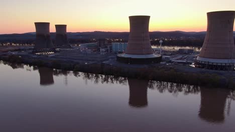 panoramica aerea della centrale nucleare sulla riva di un fiume al tramonto, produzione pulita ed ecologica di energia elettrica, concetto di energia verde