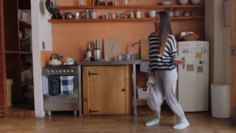 happy asian woman dancing in kitchen celebrating successful lifestyle enjoying cheerful victory dance celebration at home on weekend