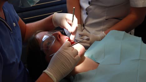 dentista examinando los dientes de un paciente bajo una luz brillante.