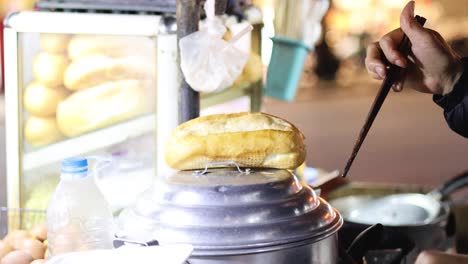 vendor assembles and serves sandwiches at night market