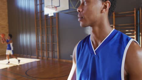 Portrait-of-african-american-male-basketball-player-with-team-in-background