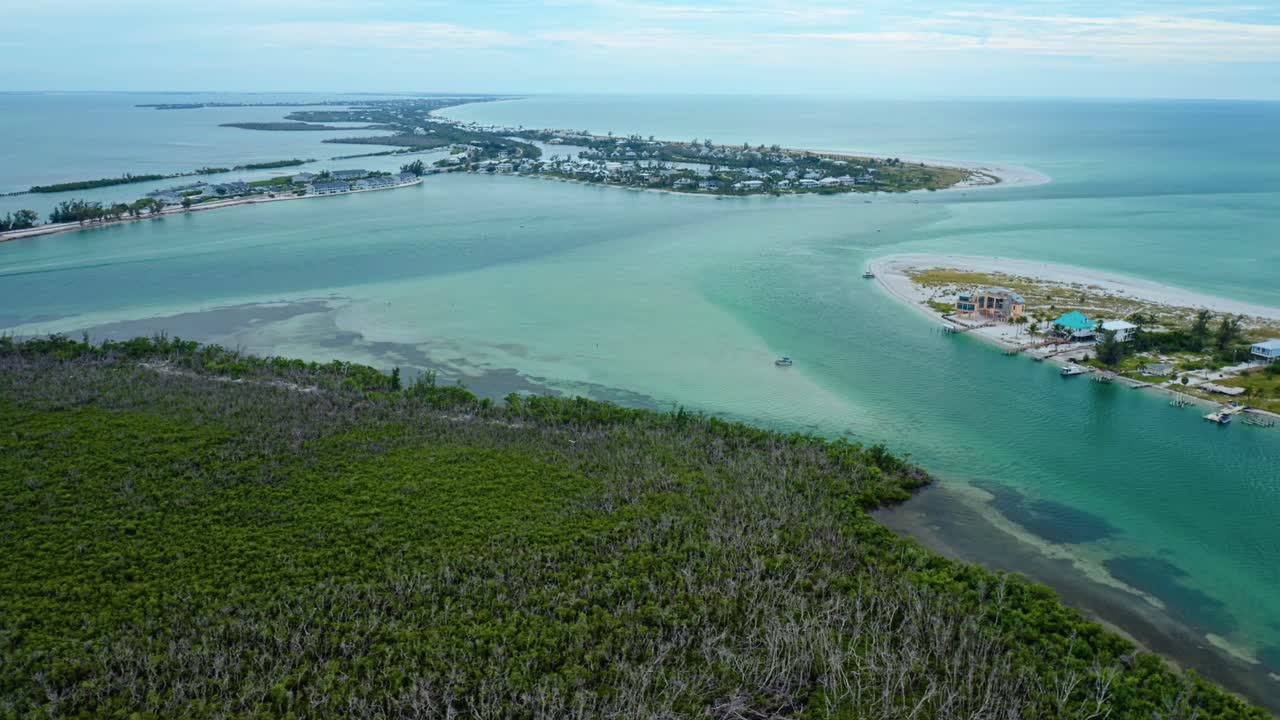 Dense mangroves frame a sweeping view of Stump Pass Inlet near Manasota Key on Florida’s Gulf Coast, where turquoise water, sandbars, and distant shoreline communities shape the coastal landscape