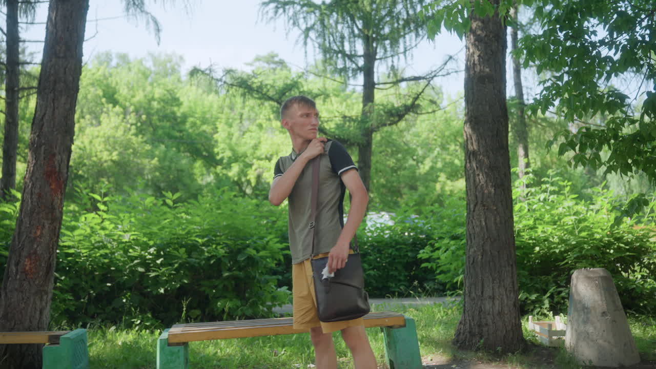 Thoughtful Individual Beneath Leafy Branches, Silent Man With Pensive Look Among Lush Park Surroundings, Solitary Figure With Introspective Gaze Resting Under Vibrant Canopy Of Green Leaves