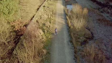 young boy riding down a country pathway on a hoverboard