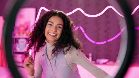 woman with curly hair smiling in front of a ring light