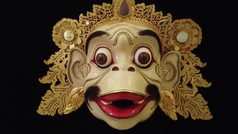 wood carved topeng monkey mask, face closeup bali indonesia traditional art, black infinite background, golden ornaments