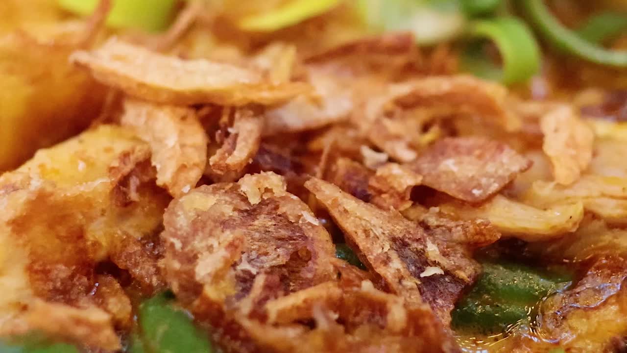 Vista macro di una saporita zuppa di noodle con guarnizioni di cipolle fritte, fagiolini e tofu