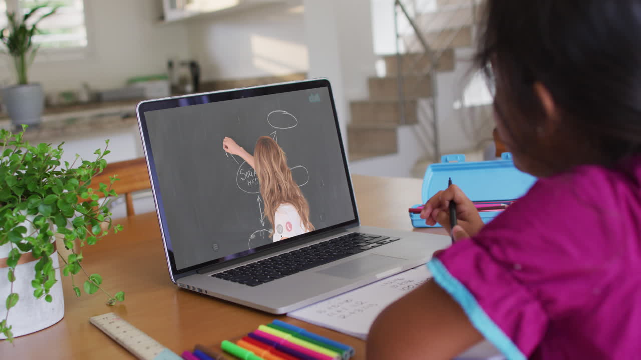 chica afroamericana haciendo la tarea mientras hace una videollamada en una computadora portátil en casa