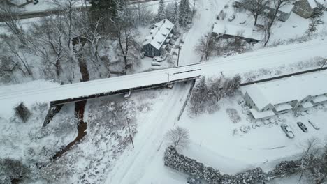 Empuje-De-Drones-Sobre-Una-Carretera-Cubierta-De-Nieve-Junto-Al-Cruce-De-Un-Arroyo-Debajo-De-Las-Vías-Del-Tren