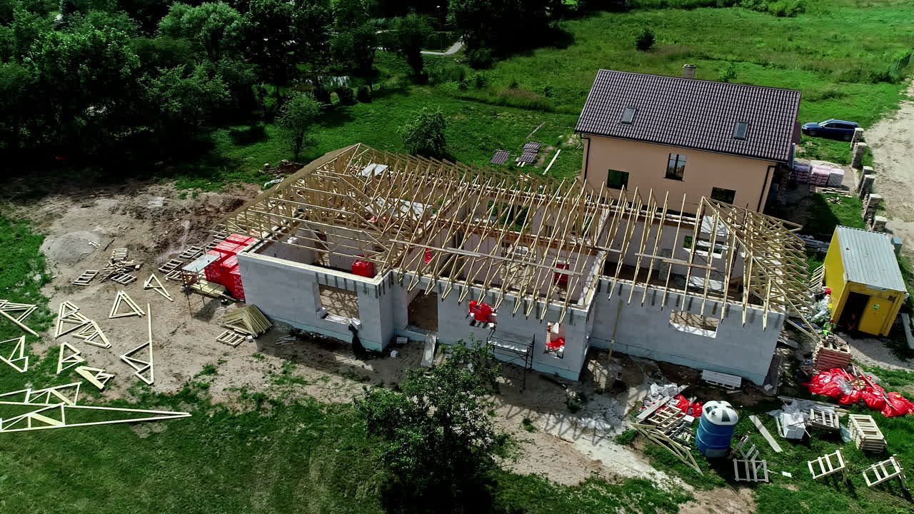 Rekaman udara rumah yang sedang dibangun dengan rangka kayu dan atap.