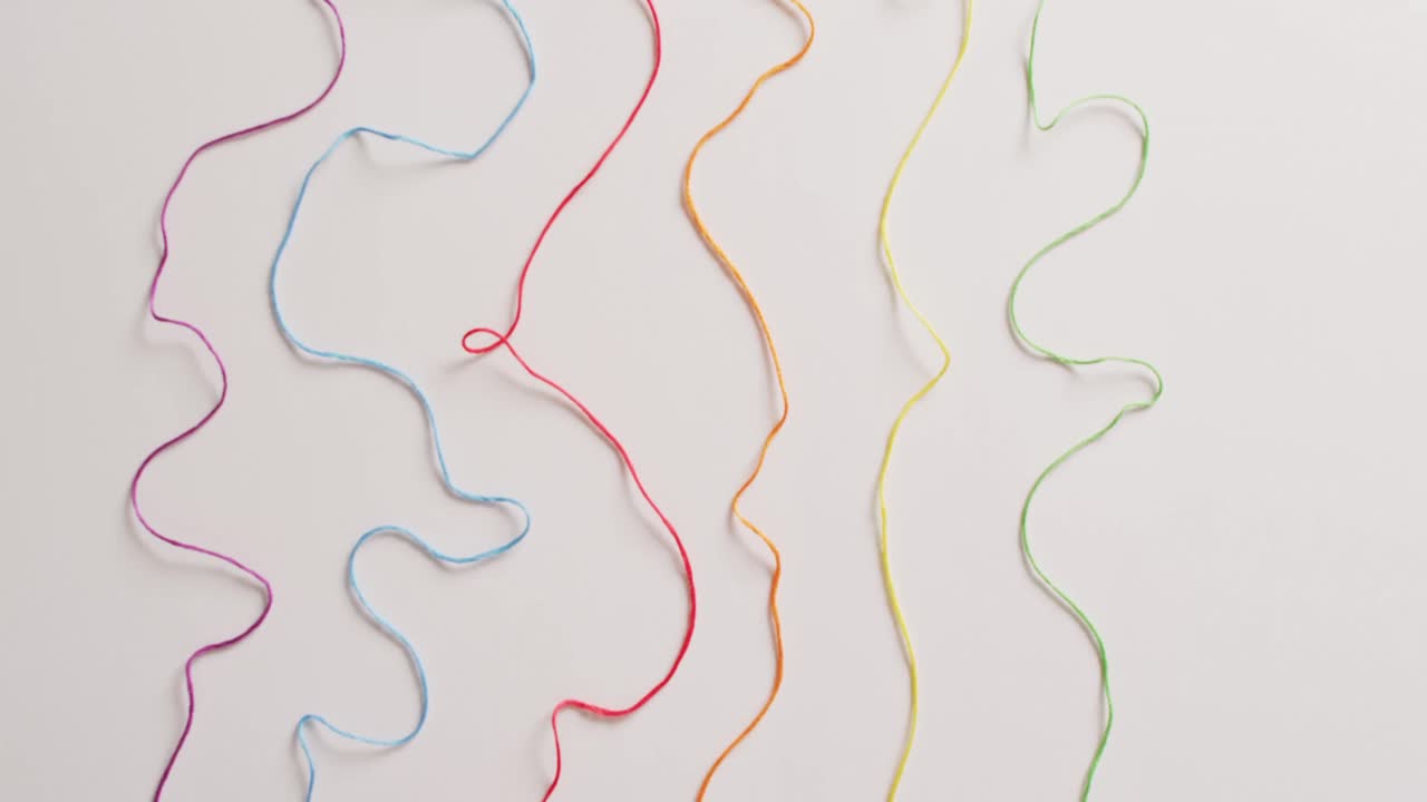 vídeo de seis bobinas de hilos de bordado de colores desenrollados sobre un fondo blanco