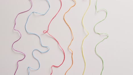 vídeo de seis bobinas de hilos de bordado de colores desenrollados sobre un fondo blanco