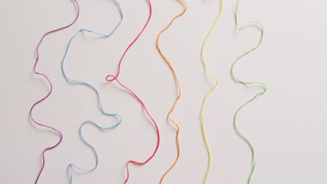 video of six bobbins of colourful embroidery threads unwound on white background