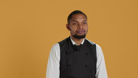 Happy-pleased-waiter-cheering-for-something-against-yellow-background