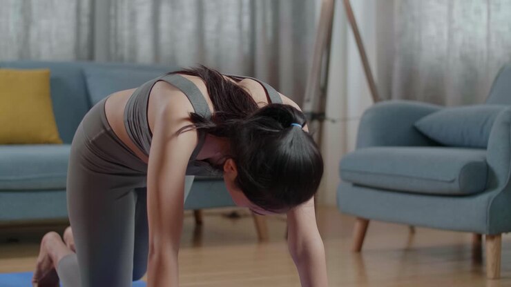 Close Up Of Young Asian Athletic Female Exercising, Stretching And Practicing Yoga At Home With Online Coach Via Laptop Computer